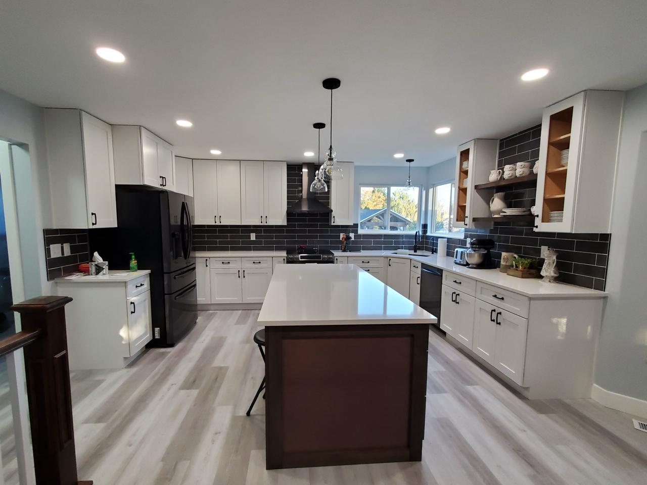 Beautifully restored kitchen with white cabinets and dark backsplash - completed by Five Point Restoration